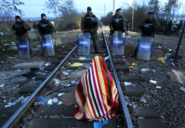 Stranded Iranian migrant Hamid, 34, an electrical engineer from the Iranian town of Sanandij sits on rail tracks in front of Macedonian riot police guarding the border between Greece and Macedonia near the Greek village of Idomeni November 23, 2015. Hamid and a dozen other Iranian migrants are on hunger-strike for a second day. (Photo by Yannis Behrakis/Reuters)