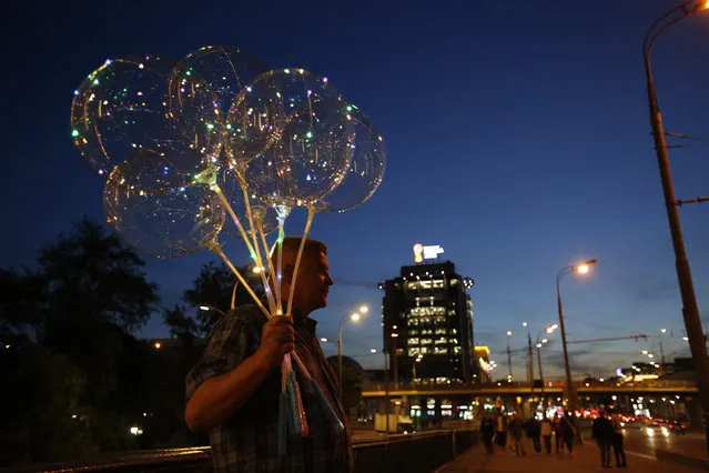 A vendor sells balloons decorated with lights on a bridge in central Moscow, Russia, during the 2018 soccer World Cup, Friday, June 15, 2018. (Photo by Rebecca Blackwell/AP Photo)