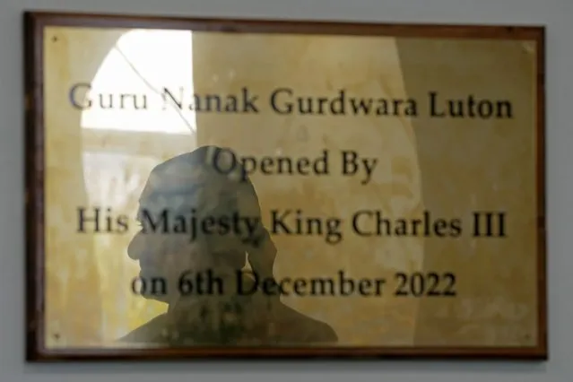 The shadow of Gurch Randhawa is reflected in a plaque commemorating King Charles III's visit to the Guru Nanak Gurdwara in Luton, England, in a photo taken on Thursday, April 27, 2023. King Charles III visited the Sikh house of worship last year as part of his efforts to build bridges with faith groups and show that the monarchy, a 1,000-year-old institution with Christian roots, can still represent the people of modern, multi-cultural Britain. (Photo by Kin Cheung/AP Photo)