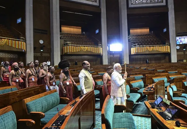 Indian prime minister Narendra Modi carries a royal golden sceptre to be installed it near the chair of the speaker during the start of the inaugural ceremony of the new parliament building, in New Delhi, India, Sunday, May 28, 2023. The new triangular parliament building, built at an estimated cost of $120 million, is part of a $2.8 billion revamp of British-era offices and residences in central New Delhi called "Central Vista", even as India's major opposition parties boycotted the inauguration, in a rare show of unity against the Hindu nationalist ruling party that has completed nine years in power and is seeking a third term in crucial general elections next year. (Photo by AP Photo)