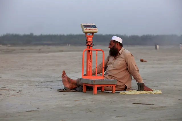 A blind man sits beside his scales waiting for customers at a picnic spot on the beach of the Sardaryab river in Charsadda outside Peshawar, Pakistan October 18, 2016. (Photo by Fayaz Aziz/Reuters)