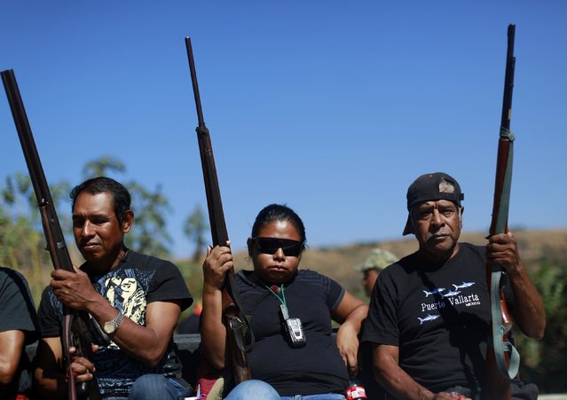 Members of the Community Police of the FUSDEG (United Front for the Security and Development of the State of Guerrero) ride with their weapons in the back of a vehicle to a celebration to mark the first anniversary of the force's operations in Ocotito, January 23, 2015. (Photo by Jorge Dan Lopez/Reuters)