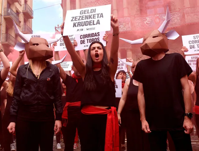 A pro- animal rights activist holds a banner that reads in Basque “Stop cruel bullfighting” during a protest against bullfighting and bull- running called by the People for the Ethical Treatment of Animals (PETA) and Anima Naturalis pro- animal groups on the eve of the San Fermin festivities in the Northern Spanish city of Pamplona on July 5, 2018. The San Fermin festival is a symbol of Spanish culture that attracts thousands of tourist to watch the bull- runs despite heavy condemnation from animal rights groups. (Photo by Ander Gillenea/AFP Photo)