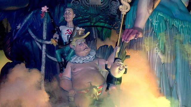 “Ninots” (cardboard figurines whose name literally means 'dolls' in Valencian) depicting North Korean leader Kim Jong Un (R), US president Donald Trump and Russia's President Vladimir Putin (L), burn on the final night of the Fallas Festival in Valencia on March 19, 2025. The “fallas” – gigantic cardboard structures depicting current events and celebrities, with individual figures known as “ninots” – are burned in the streets of Valencia on March 19 as a tribute to Saint Joseph, the patron saint of the carpenters' guild. (Photo by Jose Jordan/AFP Photo)