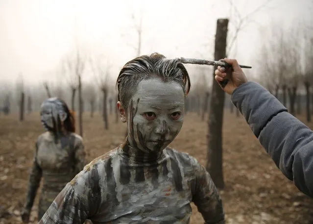 A staff paints a model with camouflage colours to blend her in with the background for Chinese artist Liu Bolin's artwork “Dongji”, or Winter Solstice, on the second day after China's capital Beijing issued its second ever “red alert” for air pollution, in Beijing, China, December 20, 2015. (Photo by Kim Kyung-Hoon/Reuters)