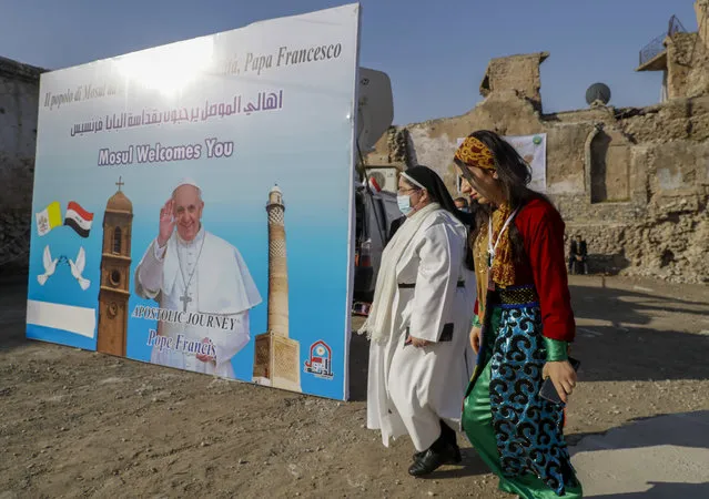 Surrounded by destroyed buildings people arrive to join Pope Francis who will pray for the victims of war at Hosh al-Bieaa Church Square, in Mosul, Iraq, once the de-facto capital of IS, Sunday, March 7, 2021. (Photo by Andrew Medichini/AP Photo)