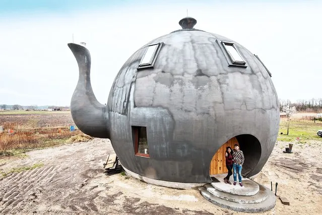 Polish artist Maciej Chesiak (R) and his wife Jenifer Penroz (L) pose in front of a house in the shape of a teapot in Makowiska village, north-central Poland, 20 April 2022. Maciej Chesiak fulfilled his dreams and built a house in the shape of a classic teapot. (Photo by Tytus Zmijewski/EPA/EFE)
