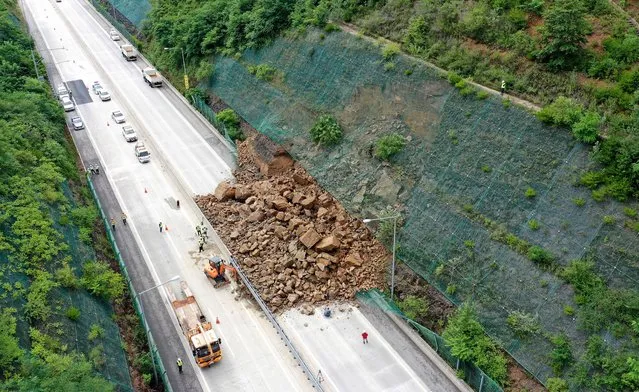 Workers clear a section of a closed expressway in Gunwi, North Gyeongsang Province, South Korea, 05 July 2023, following a landslide due to heavy rain in the region the previous day. (Photo by Yonhap/EPA)