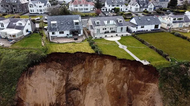 Houses are seen on the edge of a cliff after it collapsed in the village of Nefyn, Wales, United Kingdom on April 20, 2021. Picture taken with a drone. (Photo by Carl Recine/Reuters)