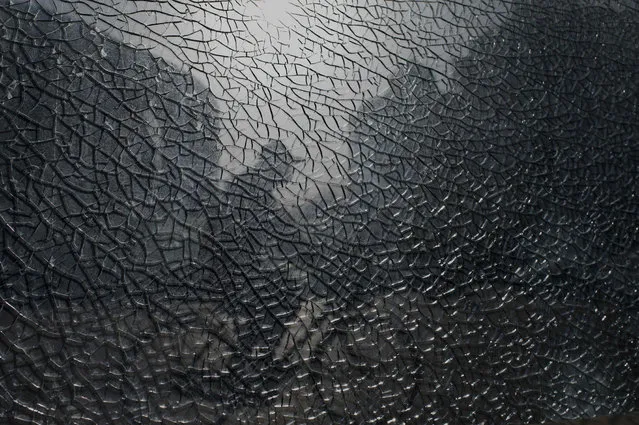 A man pedals past a shattered glass in Beijing on March 23, 2021. (Photo by Noel Celis/AFP Photo)
