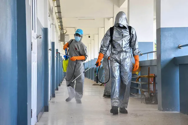 In this handout photo from the Royal Thai Army taken and released on May 21, 2021, military personnel in protective suit disinfect a school in Ubon Ratchatani province to prevent the spread of the Covid-19 coronavirus. (Photo by Royal Thai Army/Handout via AFP Photo)