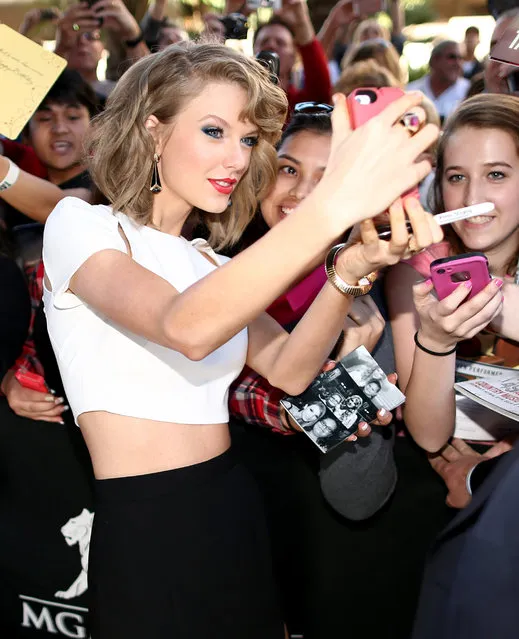 Recording artist Taylor Swift takes a selfie photo with fans during the red carpet at the 49th Annual Academy of Country Music Awards at the MGM Grand Garden Arena on April 6, 2014 in Las Vegas, Nevada. (Photo by Christopher Polk/ACMA2014/Getty Images for ACM)