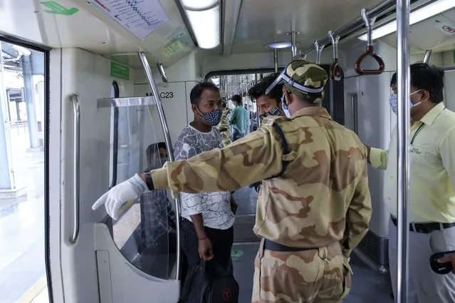 A security person asks a passenger to take the next train as Delhi Metro resumed operations at 50% capacity in New Delhi, India, Monday, June 7, 2021. (Photo by Ishant Chauhan/AP Photo)