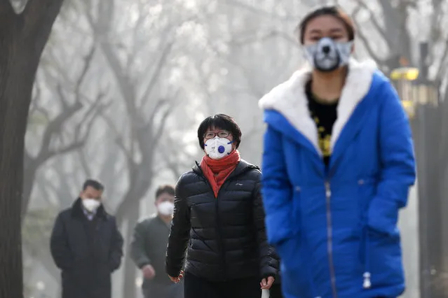Chinese people wearing masks for protection against pollution walk at Ritan Park shrouded by heavy smog in Beijing, Monday, December 19, 2016. (Photo by Andy Wong/AP Photo)