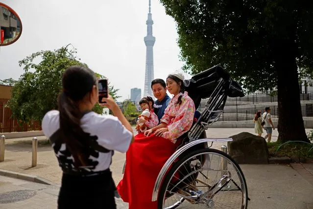 Rickshaw puller Akina Suzuki, 19, takes a photo of a family of tourists from Taiwan during her guided tour around the Asakusa district in Tokyo, Japan on June 18, 2023. (Photo by Issei Kato/Reuters)