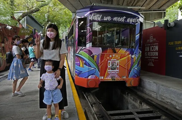 Passengers pose next to a Peak Tram on June 16, 2021. Hong Kong’s Peak Tram is a fixture in the memories of many residents and tourists, ferrying passengers up Victoria Peak for a bird’s eye view of the city’s many skyscrapers. (Photo by Vincent Yu/AP Photo)