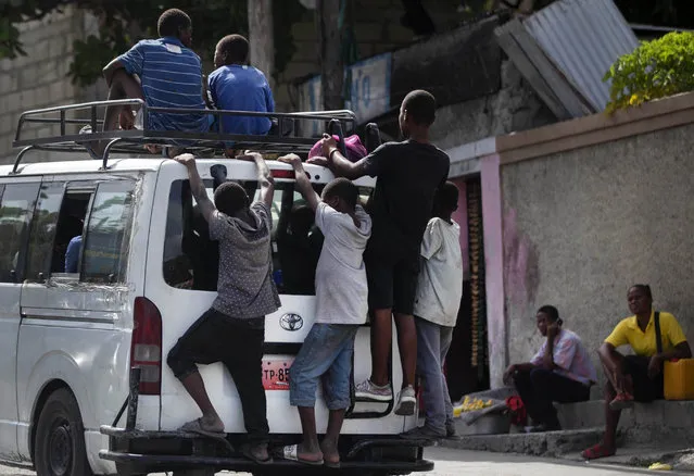 Children ride on the roof and back of a public taxi a day after the murder of President Jovenel Moise, in Port-au-Prince, Haiti, Thursday, July 8, 2021. (Photo by Joseph Odelyn/AP Photo)