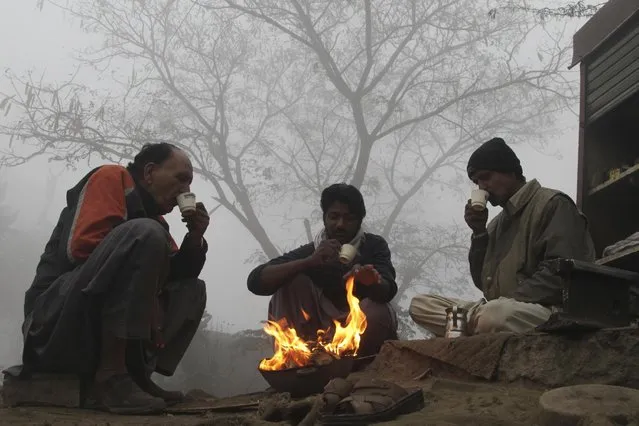 Pakistani warm themselves around a fire on a foggy day in Lahore, Pakistan, Saturday, December 24, 2016. Various cities in eastern and central Pakistan continue to experience heavy fog, disrupting air and road transportation. (Photo by K.M. Chaudary/AP Photo)