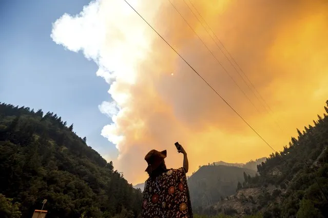 Jessica Bell takes a video as the Dixie Fire burns along Highway 70 in Plumas National Forest, Calif., on Friday, July 16, 2021. (Photo by Noah Berger/AP Photo)
