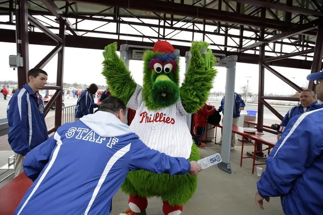 The Philadelphia Phillies' mascot, the Phillie Phanatic, is screened by security personnel for the media before an exhibition baseball game against the Pittsburgh Pirates, Friday, April 3, 2015, in Philadelphia. Citizens Bank Park has installed walk-through metal detectors to comply with Major League Baseball's new rule that all spectators be scanned before entering its stadiums. (Photo by Matt Slocum/AP Photo)