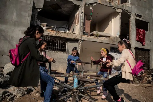 Young girls play in front of a destroyed house as they celebrate the first day of Eid al-Adha holiday in town of Beit Hanoun, northern Gaza Strip, Tuesday, July. 20, 2021. (Photo by Khalil Hamra/AP Photo)