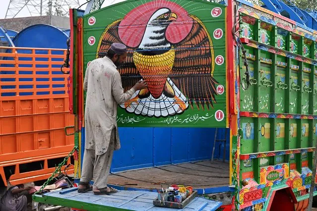A man paints a truck at his workshop in Lahore on November 6, 2023. (Photo by Arif Ali/AFP Photo)