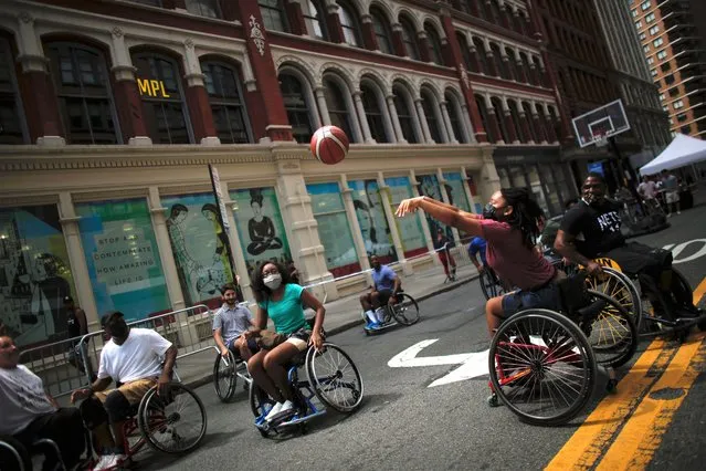 People on wheelchairs play basketball during Summer streets event in New York, on August 14, 2021 amid the Covid-19 pandemic. The annual Summer Streets event offers to New Yorkers different entertainment and activities on a seven-mile stretch of city streets from the Upper East Side to the Brooklyn Bridge. (Photo by Kena Betancur/AFP Photo)