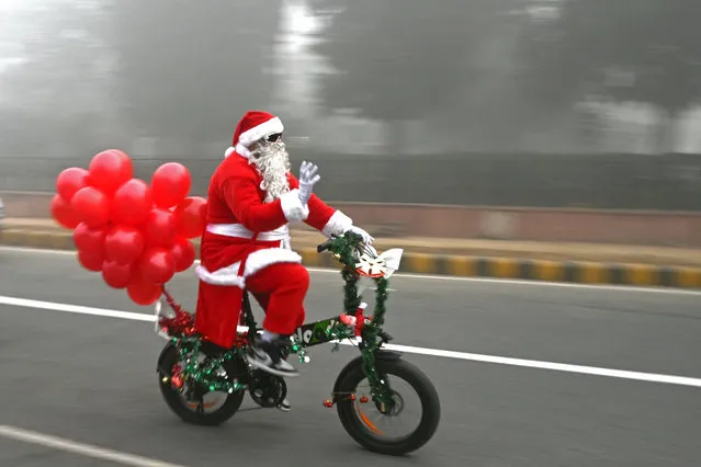 Santa Claus rides a cycle along a street engulfed in fog on Christmas in New Delhi on December 25, 2023. (Photo by Arun Sankar/AFP Photo)