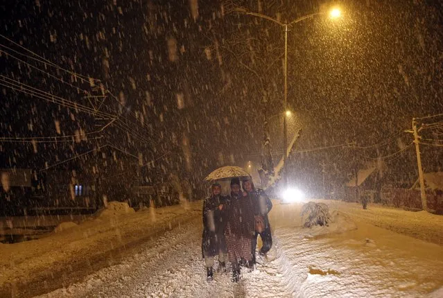 Men use an umbrella to shield themselves from snow during heavy snowfall on the outskirts of Srinagar, February 6, 2019. (Photo by Danish Ismail/Reuters)