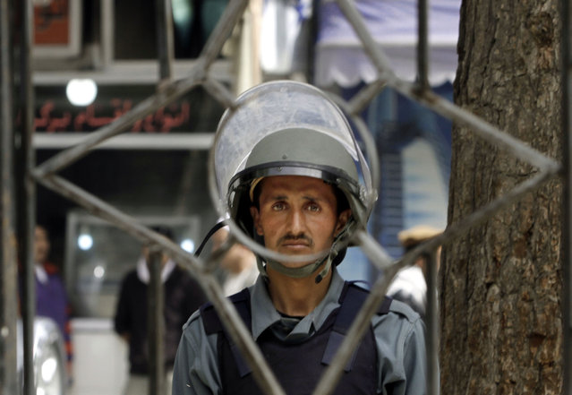 An Afghan National Policeman stands guard during a protest against the government's lack of action to try to find a group of men from the minority Afghan Shiite Hazara community who were abducted in February, in Kabul, Afghanistan, Thursday, April 16, 2015. Tens chanted slogans against the Taliban and the Islamic State group who allegedly were responsible for the kidnapping of the 31 Hazara men and boys. (Photo by Allauddin Khan/AP Photo)