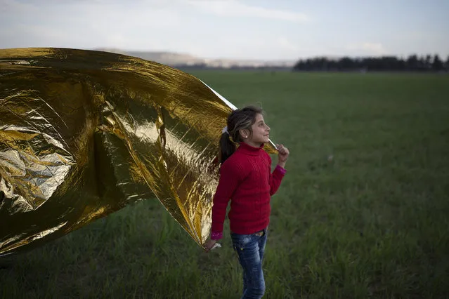 A young girls plays with a survival blanket in the wind on the Greek-Macedonia border on March 02, 2016 in Idomeni, Greece. The transit camp at the border is becoming increasingly overcrowded as thousands of refugees continue to arrive from Athens and the Greek Islands. Macedonia's border with Greece remains 'open' but after allowing 580 refugees a day to cross into the country at the beginning of the week, the numbers passing have fallen dramatically with only a handful every day. (Photo by Dan Kitwood/Getty Images)