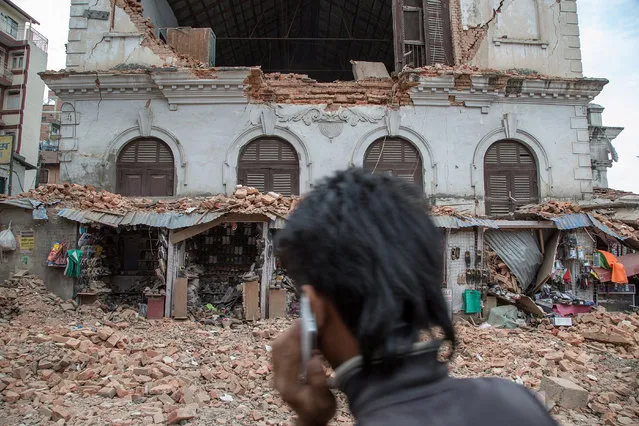 A young man speaks on the phone in front of a collapsed building in the city center following an earthquake on April 25, 2015 in Kathmandu, Nepal. (Photo by Omar Havana/Getty Images)