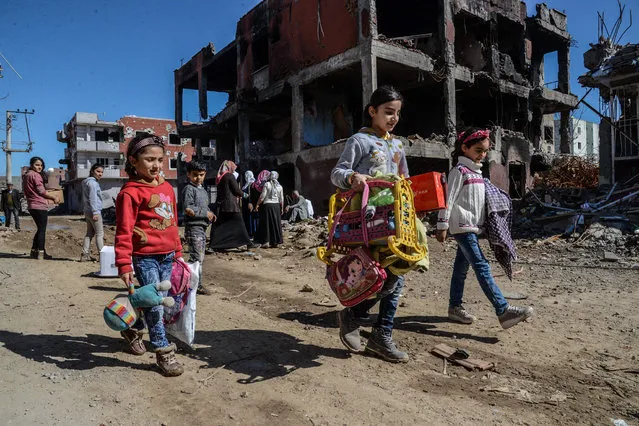 Young girls walk next to ruined houses and shops on March 8, 2016 during International Women's day in Cizre district. Residents of Cizre in southeastern Turkey began returning home Wednesday after authorities partially lifted a curfew in place since December for a controversial operation against Kurdish rebels which left many homes destroyed. (Photo by Ilyas Akengin/AFP Photo)