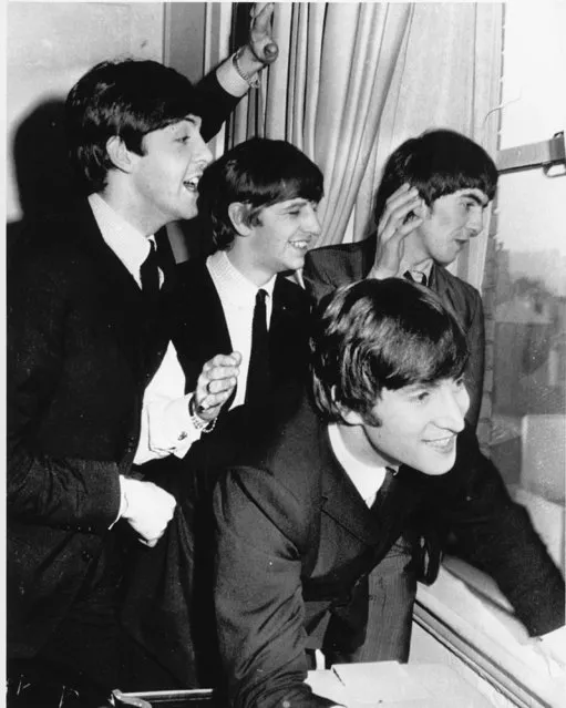 The Beatles wave to fans assembled below their Plaza Hotel window after they arrived in New York City on February 7, 1964 for a short tour of the United States. From left to right are, Paul McCartney, Ringo Starr, John Lennon, and George Harrison. (Photo by AP Photo)