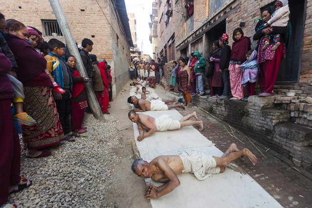 Nepalese Hindu devotees roll on the ground before taking a holy bath in the Hanumante River during the Madhav Narayan festival in Bhaktapur, Nepal, 23 January 2017. The Madhav Narayan festival is a full month-long event devoted to religious fasting, holy bathing and the study of the Swasthani book, which is dedicated to the God Shiva and Goddess Swastani. Priests or householders read a chapter of the story each day to the gathered family. Hundreds of married women and dozens of male devotees complete a month-long fast for a better life and peace in the country at various temples; unmarried women take the fast to attract a suitable husband and married women take the fast in hopes of improving their families' prosperity. (Photo by Hemanta Shrestha/EPA)