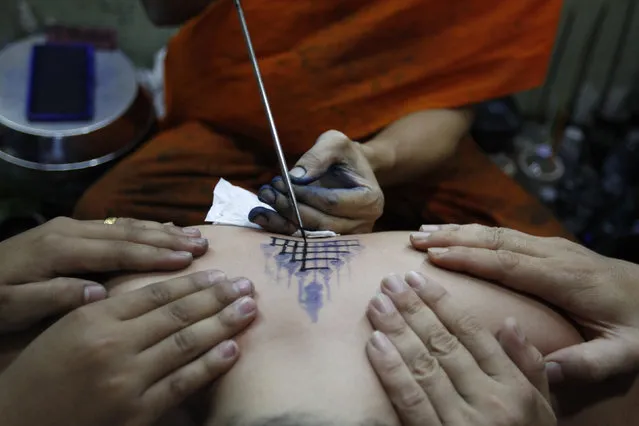 A Buddhist monk uses a traditional needle to tattoo the body of a man at Wat Bang Phra in Nakhon Pathom province on the outskirts of Bangkok, Thailand,  March 18, 2016. Believers from across Thailand travel to the monastery to have their bodies adorned with tattoos and to pay their respects to the temple's master tattooist. They believe the tattoos have mystical powers, ward off bad luck and protect them from harm. (Photo by Chaiwat Subprasom/Reuters)