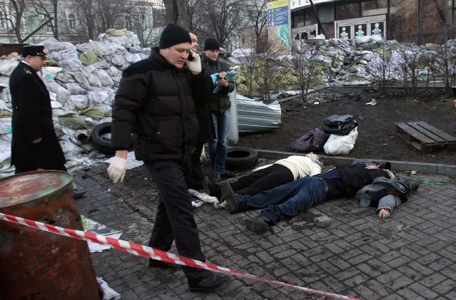 Police experts examine bodies of the dead anti-government protesters after their clashes with the police in Kiev on February 18, 2014.Ukrainian riot police stormed the main opposition camp in Kiev Tuesday after clashes left at least seven dead in the bloodiest day in three months of protests, triggering international alarm. (Photo by Anatolii Boiko/AFP Photo)