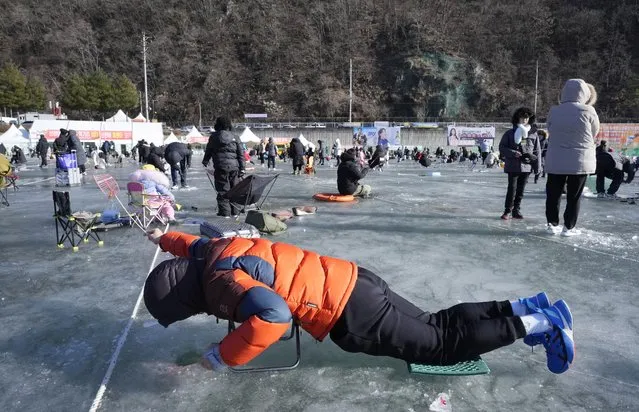 A man casts a line through a hole drilled in the surface of a frozen river during a trout catching contest in Hwacheon, South Korea, Saturday, January 6, 2024. The contest is part of an annual ice festival which draws over one million visitors every year. (Photo by Ahn Young-joon/AP Photo)