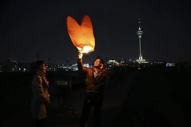 An Iranian man releases a lit lantern during Chaharshanbe Souri, or Wednesday Feast, an ancient Festival of Fire, on the eve of the last Wednesday of the solar Persian year, in Tehran, Iran, Tuesday, March 17, 2015. (Photo by Vahid Salemi/AP Photo)