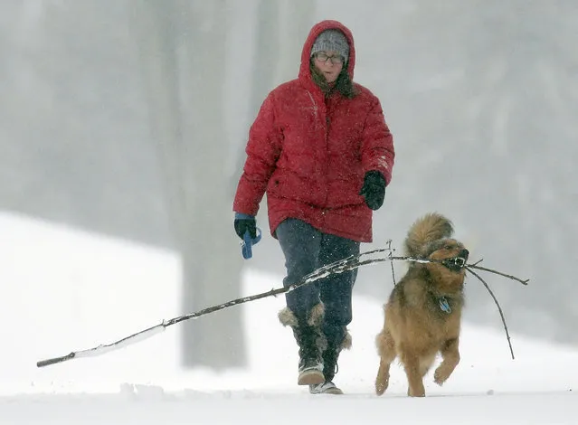 Rebecca Martin and her dog Norris enjoy their daily walk through Erb Park Thursday, March 24, 2016, in Appleton, Wis. A storm Wednesday brought heavy and blowing snow to parts of Wyoming, South Dakota, Nebraska, Iowa, Minnesota, Wisconsin and Michigan. Up to a foot of snow fell in the southern Twin Cities and Wisconsin Gov. Scott Walker called members of the National Guard to active duty to help local authorities. (Photo by Dan Powers/The Post-Crescent via AP Photo)
