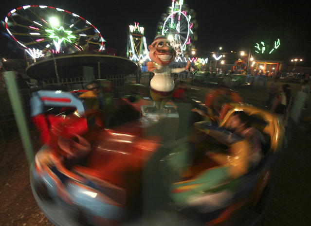 Children ride a merry-go-round during dusk at a fair in Chandigarh, India October 11, 2011. (Photo by Ajay Verma/Reuters)