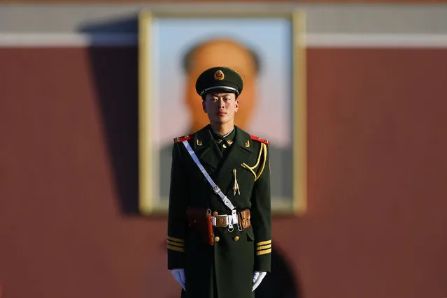 A paramilitary policeman stands guard in front of a portrait of China's late leader Mao Zedong near the Great Hall of the People at Tiananmen Square during the opening session of the National People's Congress (NPC) in Beijing March 5, 2014. China announced on Wednesday it would maintain its economic growth target for 2014 at about 7.5 percent, as expected, signalling that its policy focus would be slanted in favour of reforms and rebalancing the economy. (Photo by Petar Kujundzic/Reuters)