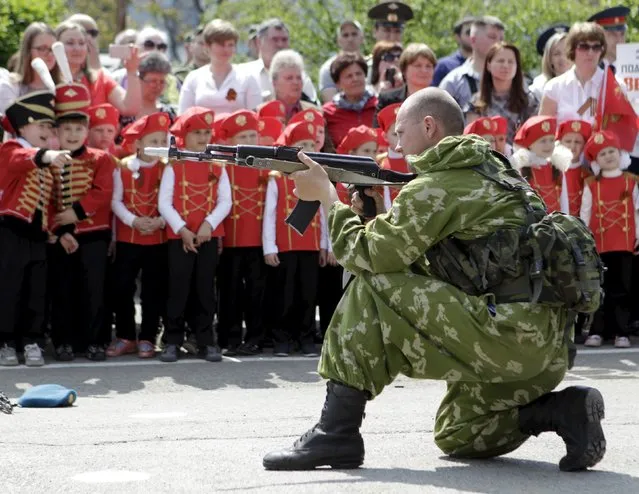 A Russian paratrooper performs as children gather in the background during the so-called parade of children's troops in Rostov-on-Don, southern Russia, May 14, 2015. (Photo by Eduard Korniyenko/Reuters)
