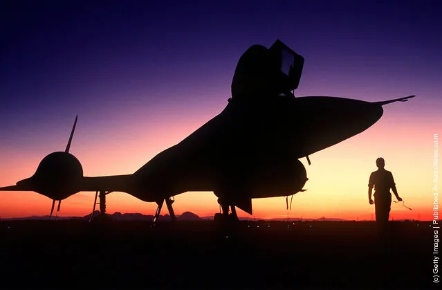 A right front view of an SR-71B Blackbird strategic reconnaissance training aircraft, silhouetted on the runway at sundown