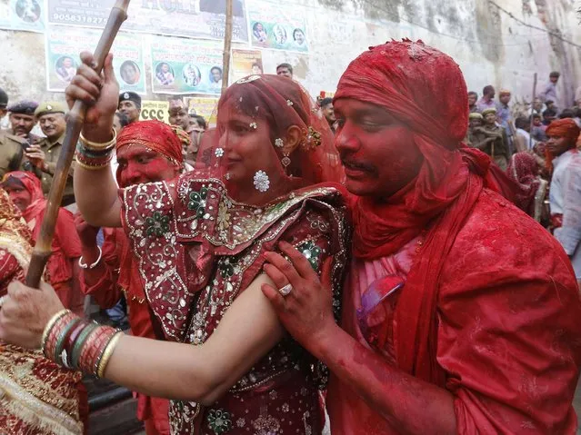 Indian women beat men with wooden sticks as they shield themselves during the annual Lathmar Holi festival in Barsana village. (Photo by Harish Tyagi/EPA)