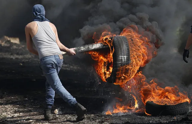 A Palestinian protestor carries a burning car tire during clashes with Israeli security forces following a weekly demonstration against the expropriation of Palestinian land by Israel in the village of Kfar Qaddum, near Nablus, in the occupied West Bank on February 24, 2017. (Photo by Jaafar Ashtiyeh/AFP Photo)