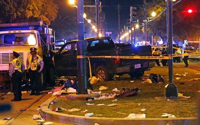 Police stand next to a pickup truck that slammed into a crowd and other vehicles, causing multiple injuries, coming to a stop against a dump truck, during the Krewe of Endymion parade in New Orleans, Saturday, February 25, 2017. (Photo by Gerald Herbert/AP Photo)