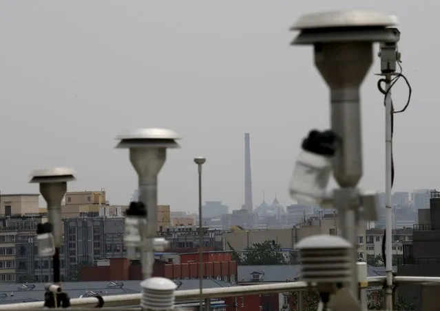 A chimney is seen framed in the background by devices for collecting samples of Beijing's air, which are installed on the rooftop of the air quality forecast and warning center, in Beijing, China, May 21, 2015. Beijing's city government organized a media tour on Thursday to its environmental protection monitoring center and a gas-fired thermoelectricity power plant to showcase its efforts to promote clean energy transformation. (Photo by Kim Kyung-Hoon/Reuters)