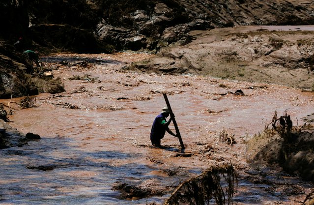 A man uses a stick to cross a river after heavy flash floods wiped out several homes when a dam burst, following heavy rains in Kamuchiri village of Mai Mahiu, Nakuru County, Kenya on April 29, 2024. (Photo by Thomas Mukoya/Reuters)