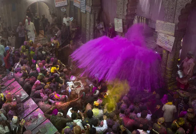 Hindu priests throw color powders at the devotees inside Banke Bihari temple, dedicated to Lord Krishna, during Holi festival celebrations in Vrindavan, India, Wednesday, March 8, 2017. Holi, the festival of colors, celebrates the arrival of spring. (Photo by Manish Swarup/AP Photo)